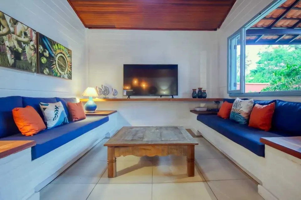 Sala iluminada com sofás embutidos e televisão